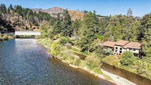 A riverside property with a house, a bridge, and dense forest. - On Mckenzie River! Home w/ Scenic Sunroom (Vida)