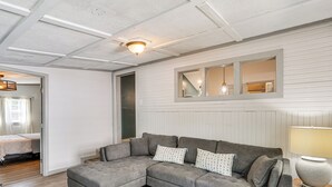 Una sala de estar moderna con un sofá modular, piso de madera y techo con vigas a la vista.
