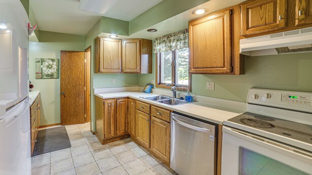 A kitchen with wooden cabinets, a stainless steel sink, and a white stove.