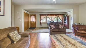 A spacious living room with a brown leather sofa, a patterned throw pillow, and a large area rug.