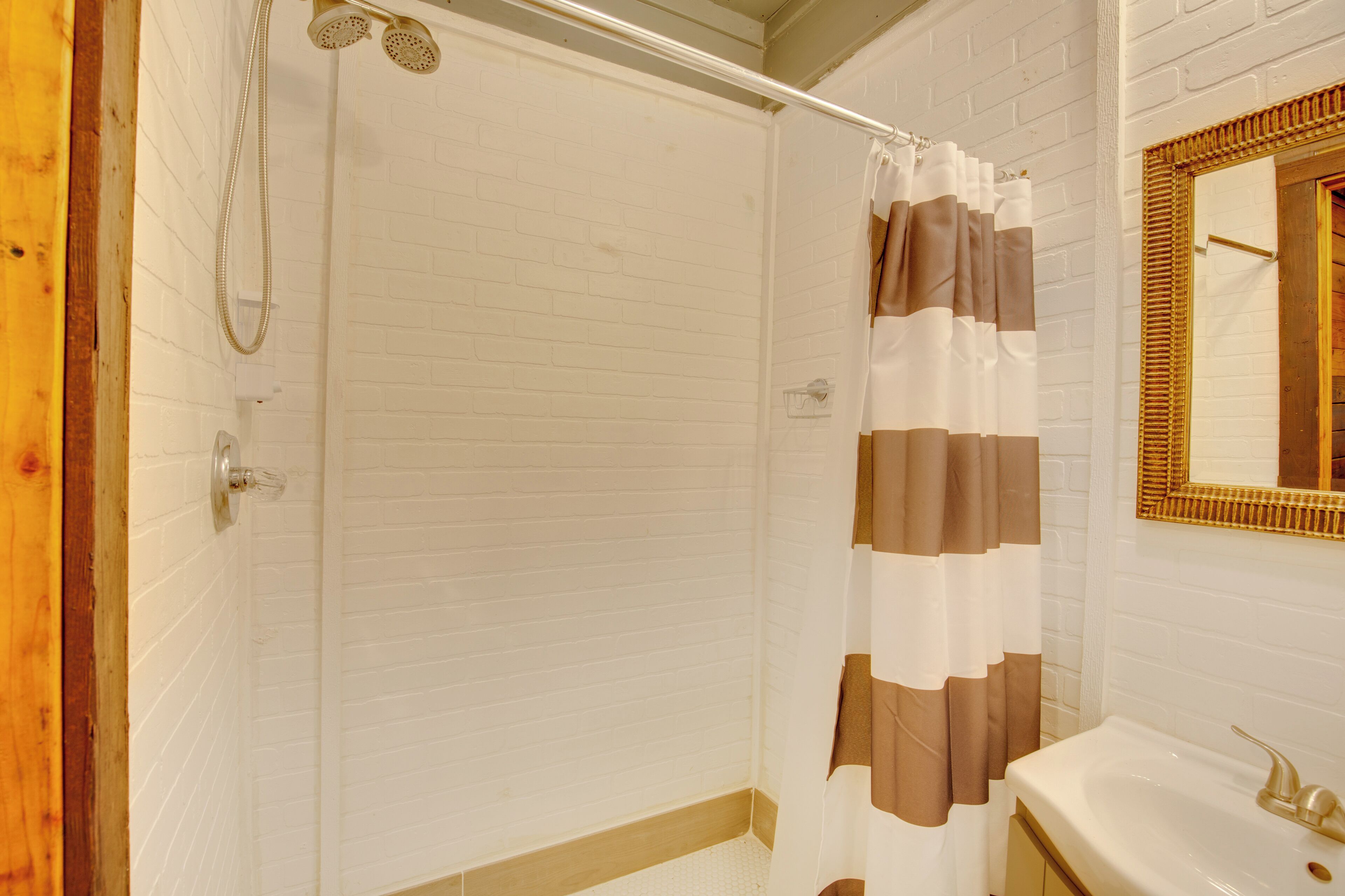 A bathroom with a shower, a sink, and a mirror.
