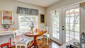 A dining area with a wooden table, white chairs, a red stool, and a window with a view of the outside. - Boqsue River Valley Views! 3-acre Country Home (Valley Mills)
