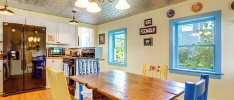 A kitchen with a wooden table, chairs, and a refrigerator.