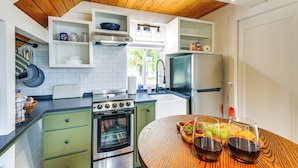 Een moderne keuken met witte kasten, een houten plafond en een eethoek met een tafel gedekt voor twee personen.