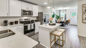 A modern kitchen with white cabinets, stainless steel appliances, and a marble countertop. - Modern Comforts + Fenced Yard: Princeton Retreat! (Princeton)