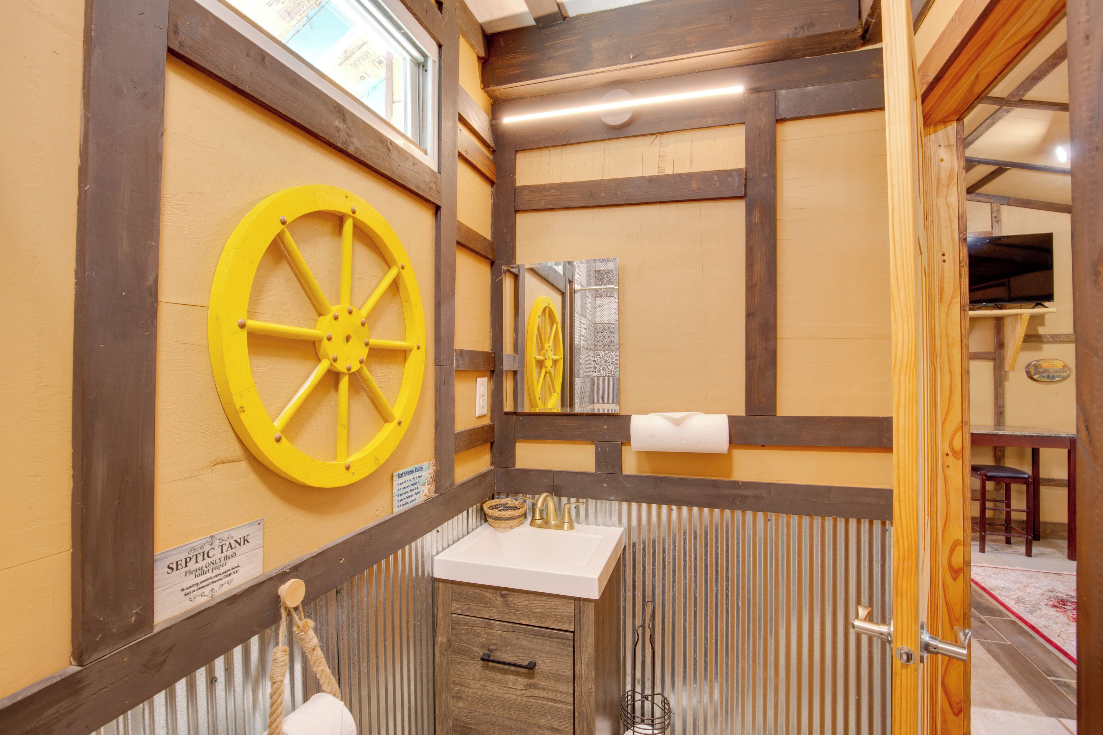 A bathroom with a wooden vanity, a yellow wheel, and a sign indicating a septic tank.