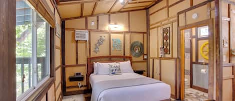 A wooden-framed bedroom with a bed, a nightstand, a window, and a door.
