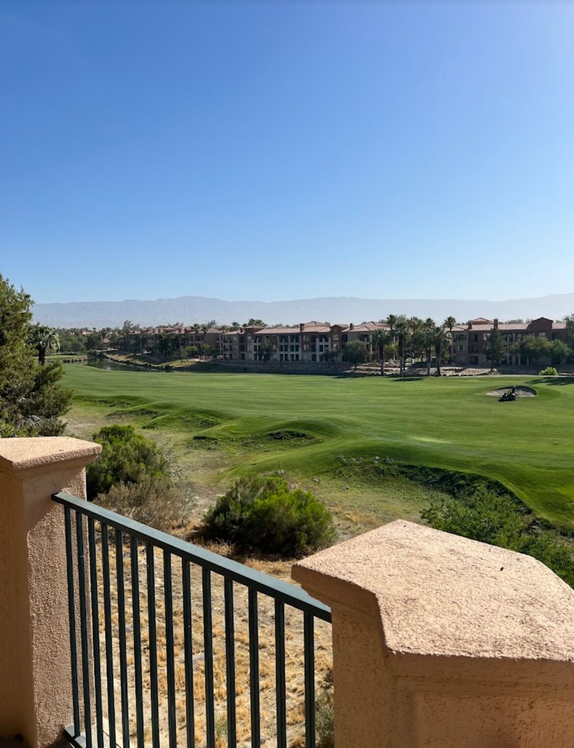 Ein Golfplatz mit Blick auf einen Gebäudekomplex im Hintergrund.