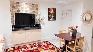 Uma cozinha compacta com painel de azulejos, uma mesa de jantar com cadeiras e um tapete estampado.