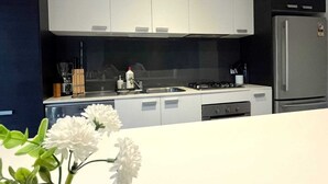 A modern kitchen with white cabinets, a stainless steel refrigerator, and a gas stove.