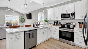 A modern kitchen with white cabinets, stainless steel appliances, and a central island. - Tranquil Waterfront Retreat: Stunning Bay Views Near Downtown Bay St. Louis (Bay St. Louis)