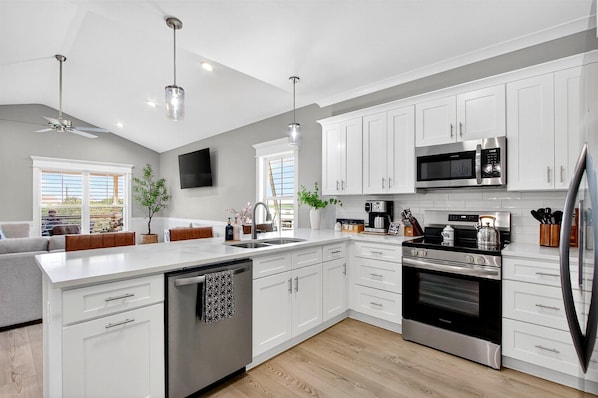 A modern kitchen with white cabinets, stainless steel appliances, and a central island.