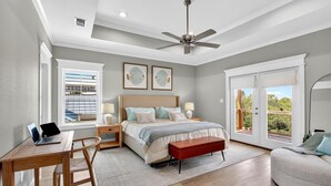 A bedroom with a bed, a desk, a laptop, a ceiling fan, and large windows. - Tranquil Waterfront Retreat: Stunning Bay Views Near Downtown Bay St. Louis (Bay St. Louis)