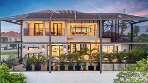 A modern two-story house with a covered patio, large windows, and a view of the surrounding landscape. - Spacious Luxury Waterfront Retreat with Pool & Spa (Naples)