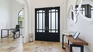 Un intérieur moderne avec une porte double noire, un bureau avec une chaise et un banc.