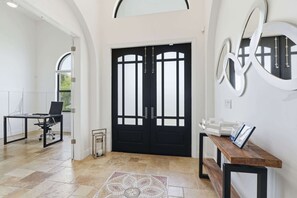 A modern interior with a black double door, a desk with a chair, and a bench. - Spacious Luxury Waterfront Retreat with Pool & Spa (Naples)