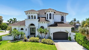 A large, white, multi-story house with a tiled roof, multiple arches, and a garage. - Spacious Luxury Waterfront Retreat with Pool & Spa (Naples)