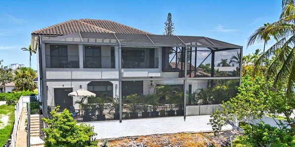 Ein zweistöckiges Haus mit Balkon, Pool und Blick auf Palmen.