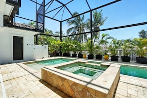 A pool area with multiple swimming pools, surrounded by potted plants and palm trees. - Spacious Luxury Waterfront Retreat with Pool & Spa (Naples)