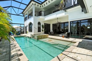 A modern house with a swimming pool, outdoor seating, and large windows. - Spacious Luxury Waterfront Retreat with Pool & Spa (Naples)