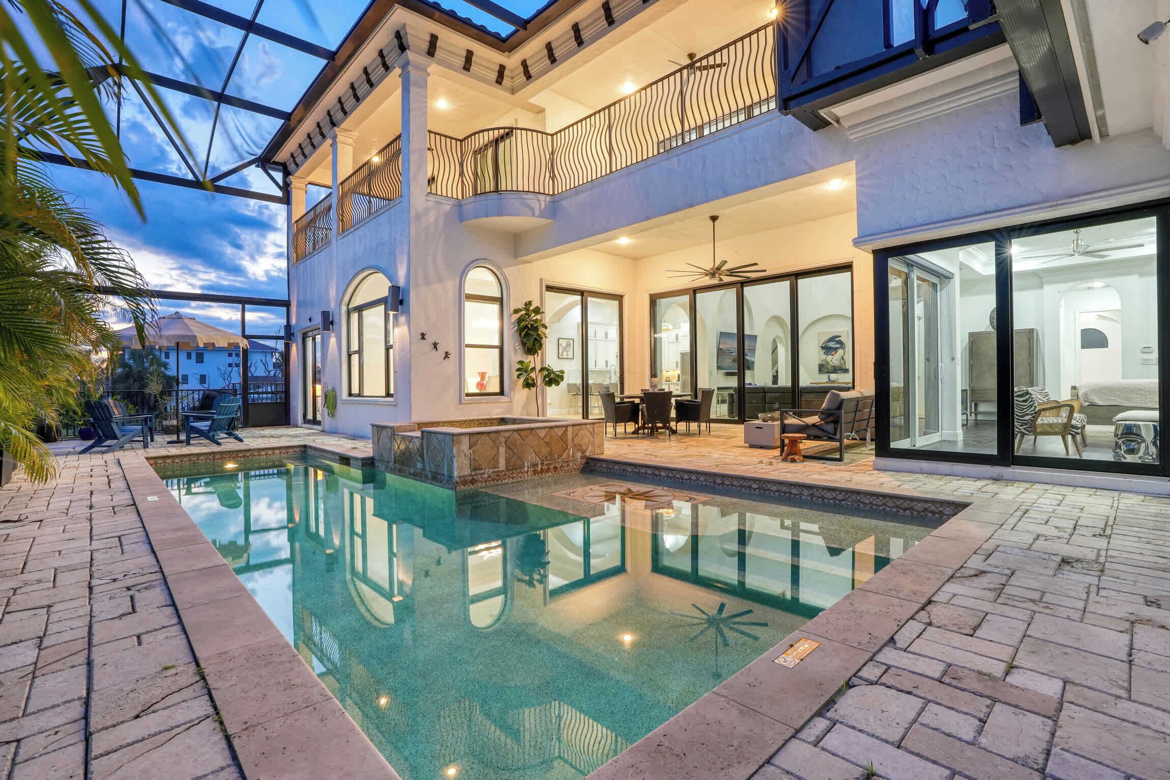 A two-story house with a swimming pool, outdoor seating, and a balcony.