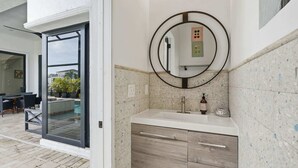 Une salle de bain avec un miroir rond, un lavabo et un meuble en bois.