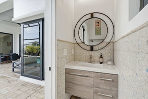 A bathroom with a round mirror, a sink, and a wooden cabinet. - Spacious Luxury Waterfront Retreat with Pool & Spa (Naples)