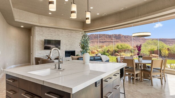 A modern kitchen with a large island, built-in appliances, and a dining area with a view of the desert landscape.