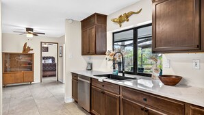A kitchen with wooden cabinets, a large window, and a view of the outdoors.