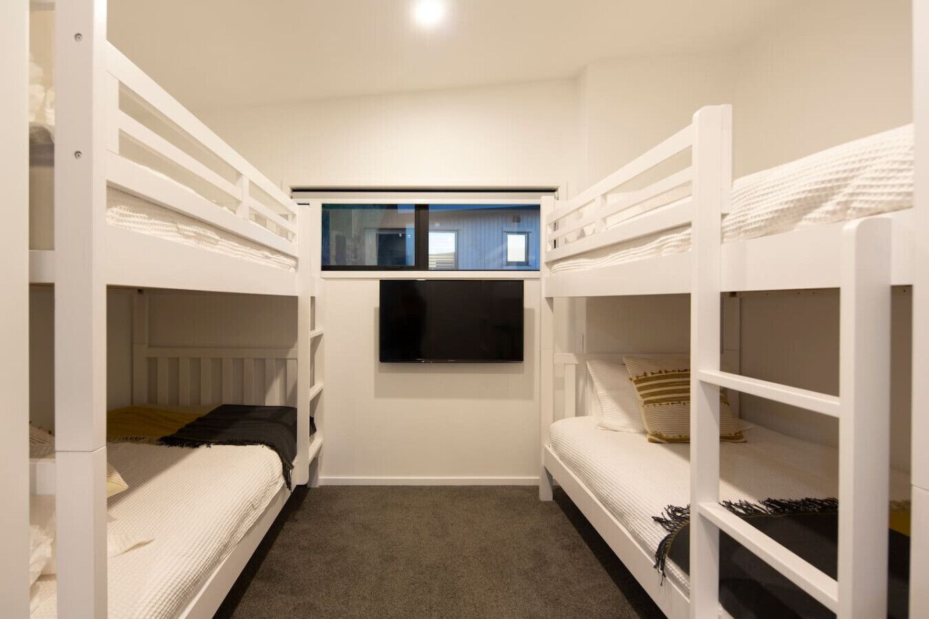 Une chambre avec des lits superposés et un téléviseur fixé au mur.