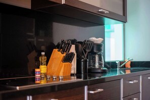 Un plan de travail de cuisine avec un range-couteaux, une machine à café et une bouteille d’huile.