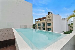 A swimming pool with a wooden deck, surrounded by buildings with a sign reading "SOUL BEACH HOTEL WITH SPAURTY."