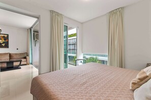 Une chambre d’hôtel avec un grand lit, un canapé, une petite table et un balcon donnant sur la ville.