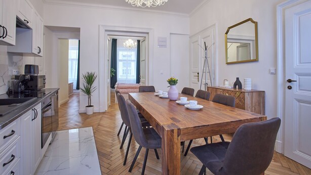 Una cocina moderna con armarios blancos, una mesa de comedor de madera y una araña.