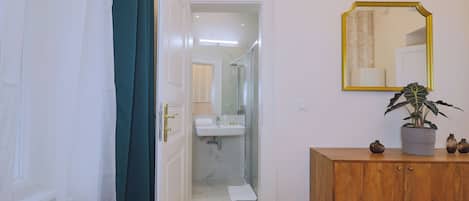 Une salle de bain avec un lavabo blanc, un miroir et un meuble en bois agrémenté d’objets décoratifs.