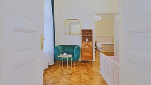 Un pasillo con un sofá color turquesa, una mesita redonda y un mueble de madera con cajones.