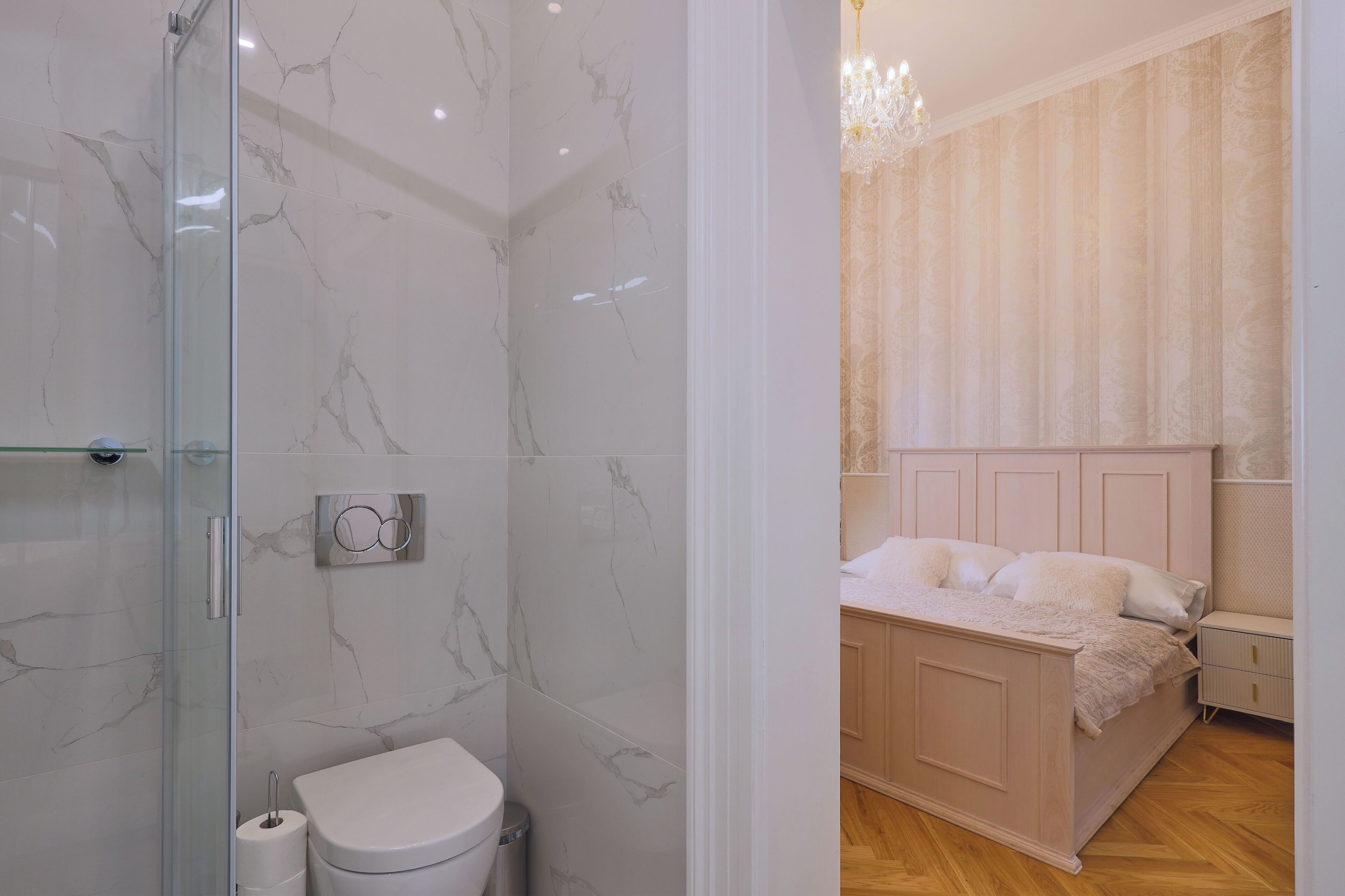 A bathroom with a glass shower enclosure and a toilet.