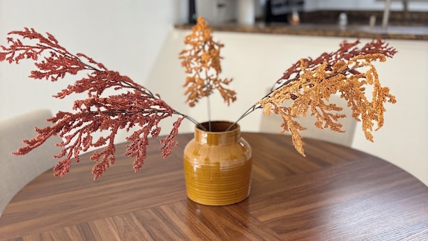 Ein runder Holztisch mit einer Vase, gefüllt mit getrockneten Ästen.