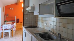 A compact kitchen with a sink, a microwave, and a small dining area with a table and chairs.