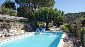 A swimming pool with lounge chairs and a stone wall.