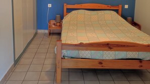 A bedroom with a wooden bed, a nightstand, a lamp, and a wardrobe.