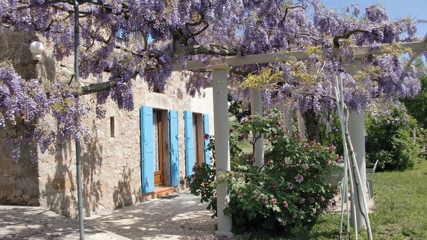 A stone building with blue shutters and a covered walkway.