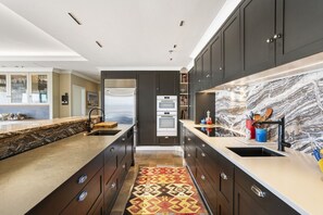 Een moderne keuken met donkere kastjes, een marmeren spatwand en een centraal keukenblok.