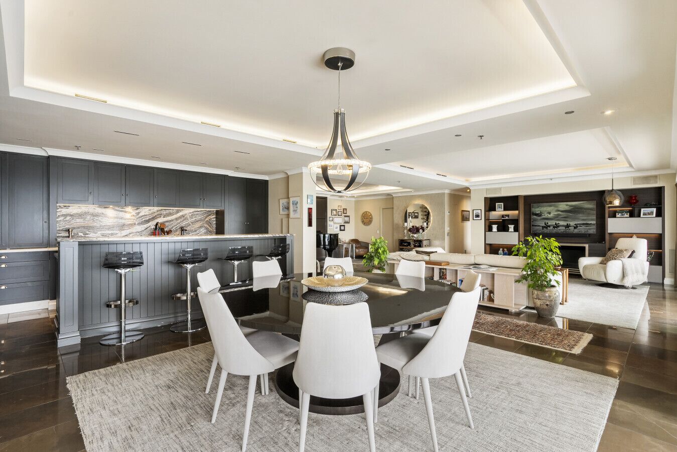 Una cocina moderna con armarios oscuros, encimera de mármol y una isla central con taburetes de bar.