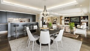 Una cocina moderna con armarios oscuros, encimera de mármol y una isla central con taburetes de bar.