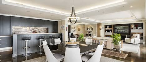 Una cocina moderna con armarios oscuros, encimera de mármol y una isla central con taburetes de bar.