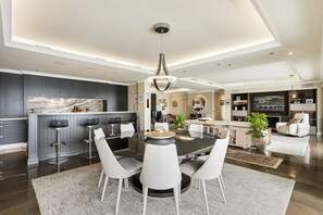 A modern kitchen with dark cabinetry, a marble countertop, and a central island with bar stools.