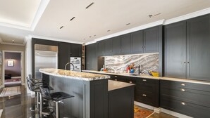 Una cocina moderna con armarios oscuros, salpicadero de mármol y una isla central con taburetes de bar.