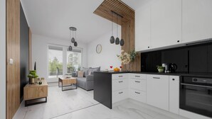 Eine moderne Küche mit weißen Schränken, einer schwarzen Kücheninsel und einem eingebauten Backofen.