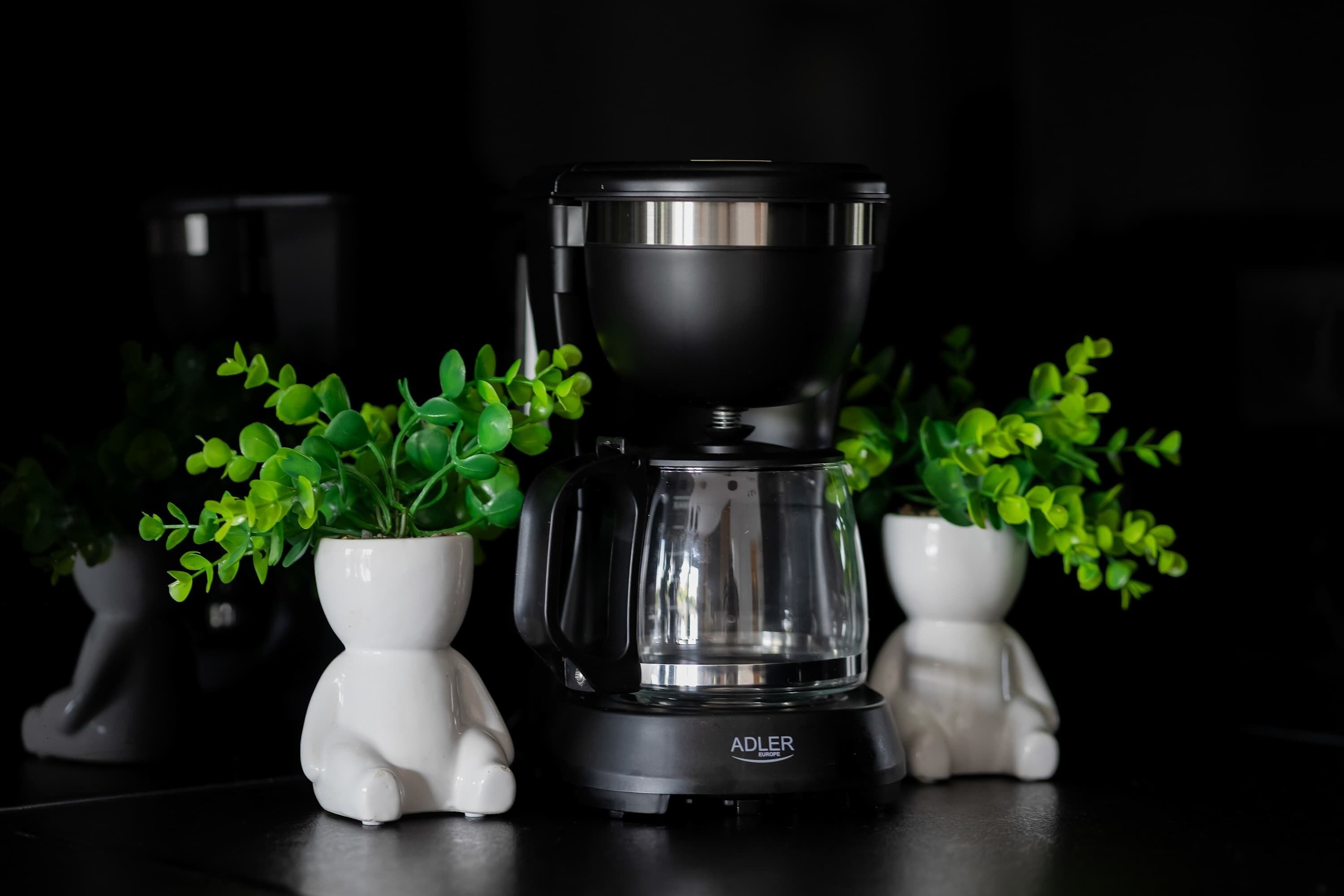 A coffee maker with a clear water reservoir, placed on a dark surface.